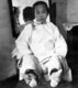 China: A woman exposing her naked bound feet to reveal their deformed shape, early 20th century